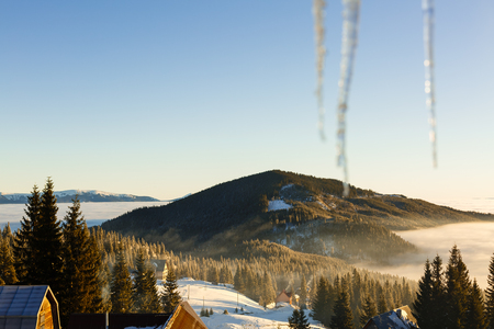 Long icicles. View from window. Blue sky and mountains on background icicles on a background of mountainsの写真素材