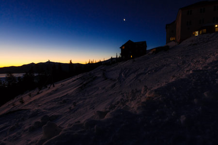 Wooden house with a light in the window. Night landscape in winter house and stars in winter...