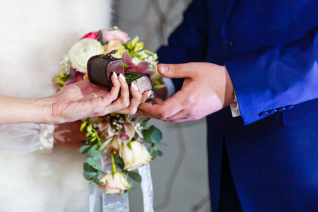 Bride gives an engagement ring to her Groom. Wedding and honeymoon concept. wedding day. focus on hand and ring.の写真素材