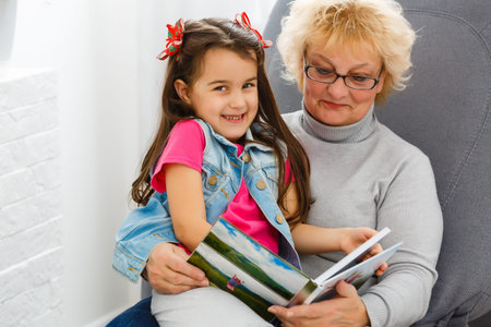 Grandmother and little granddaughter watching family photo album, relationship
