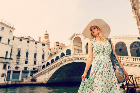 Woman tourist travel in Italy. Young girl with a white hat in venice on an old street. Girl traveling to Venice.の写真素材