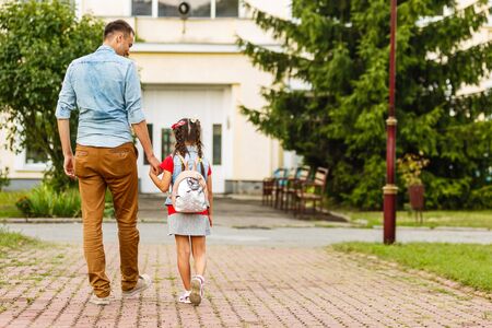 first day at school. father leads a little child school girl in first gradeの写真素材