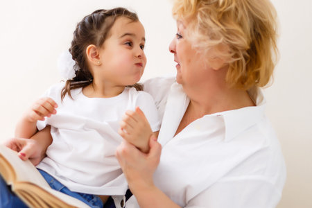 Grandmother reading a tale to her baby granddaughter. Family Reading Leisure. Quality Time. Happy...