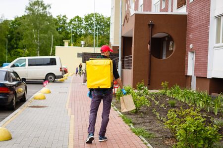 delivery, mail and people concept - happy man delivering food in disposable paper bag to customer homeの写真素材
