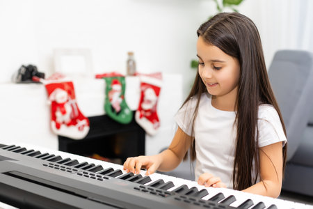 Cute little girl play Christmas melody on piano, merry Christmas celebration, happy seasonal holidaysの写真素材