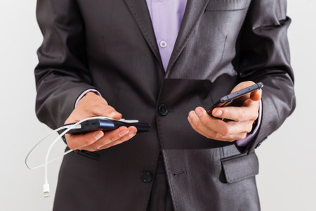 man holds a smartphone and an external battery on a white backgroundの写真素材