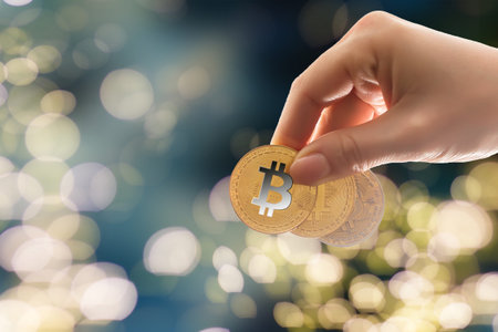 A girl holds a Bitcoin coin in hand against the background of trading charts. Cryptocurrency
