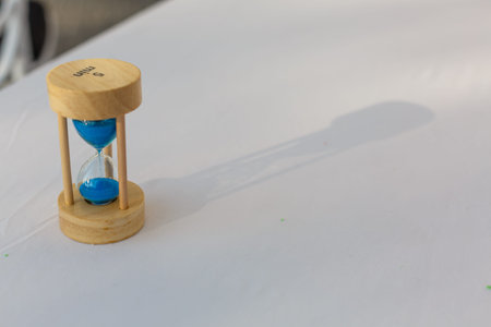Sand running through the bulbs of an hourglass measuring the passing time in a countdown to a...