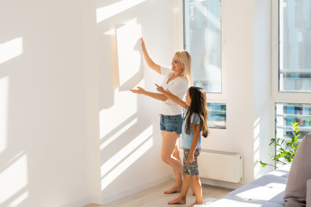 mother and daughter hangs a large photo canvas at homeの写真素材