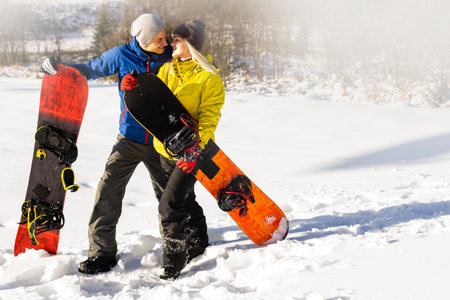 Portrait of happy couple of snowboarders outside during winter vacationsの写真素材