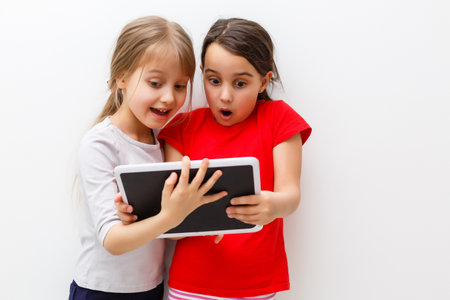 picture of two beautiful girls with tablet pc on white backgroundの写真素材