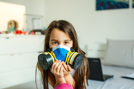 Close-up view of little girl in a big protective mask against viruses and dust in the air.の写真素材