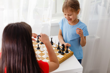 Two little sister playing chess at homeの写真素材