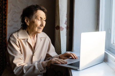 Senior woman use laptop. She looks very surprised. Surfing in a browser and social media. Laptop on the table. Using technology in old age conceptの写真素材