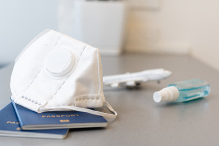 Plane toy, passport, face mask on gray background. Flight cancellation due to the impact of pandemicの写真素材