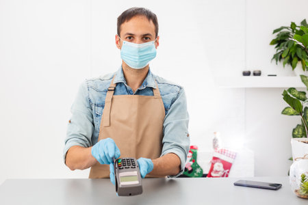 Credit card machine for money transaction. hand in gloves with credit card swipe through pos terminal and enter pin code. Banking services of electronic money. Financial success and safetyの写真素材