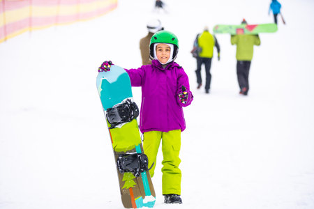 Little Cute Girl Snowboarding at ski resort in sunny winter day.の写真素材