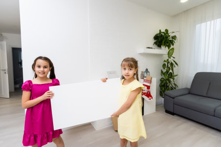 two little girls standing with empty horizontal banner in hands, a photo canvasの写真素材