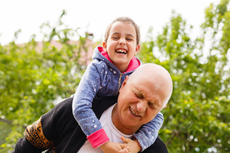 Little girl spending time with grandfather in the park.