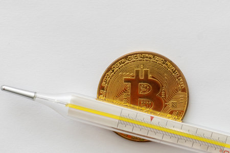 Mercury thermometer and bitcoin on white backgroundの写真素材