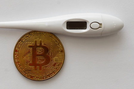 Mercury thermometer and bitcoin on white backgroundの写真素材