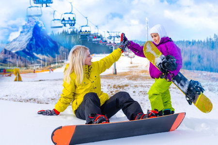 mother and daughter with snowboards in a mountain resortの写真素材