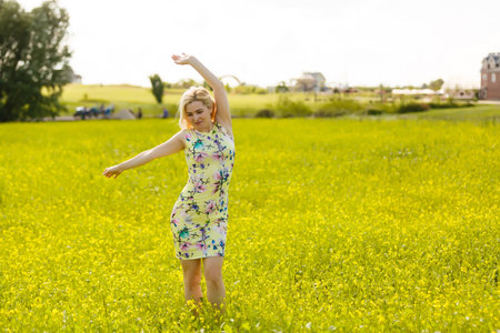Young woman with her arms wide spread is enjoying in the sunny summer day, rear viewの写真素材