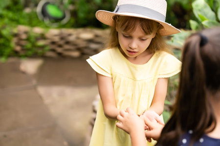 Two little sisters holding a butterfly in their hands. Children exploring nature. Family leisure with kids at summer.の写真素材