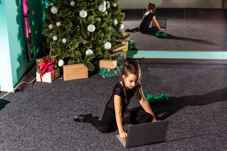Little girl doing cross-twine exercising. Doing a full split in Christmas interior