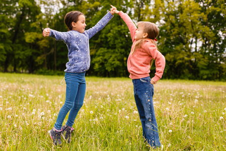 Two adorable girls dancing on the meadowの写真素材