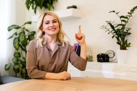 Portrait of a cheerful businesswoman sitting at the table in office and looking at cameraの写真素材