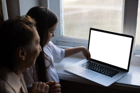 great-grandmother and granddaughter with laptop onlineの写真素材