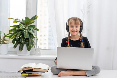 Little girl studying online using her laptop at home