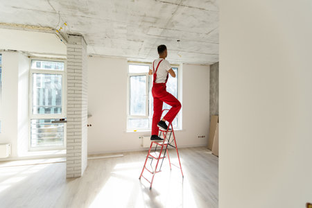 Electrician fixing halogen lamp in ceiling light in roomの写真素材