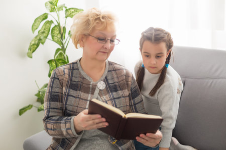 Grandmother is reading a book to her granddaughter