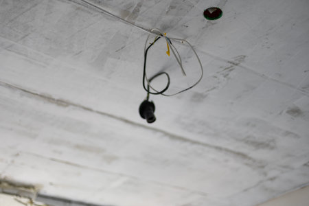 old halogen lamp hanging on electric wires from plasterboard false ceiling