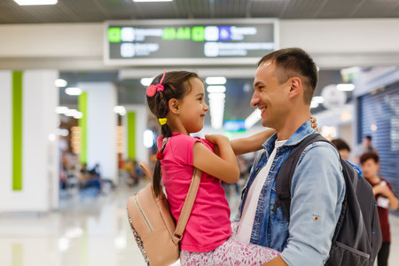Daddy is embracing girl in the airport hall with happiness.の写真素材