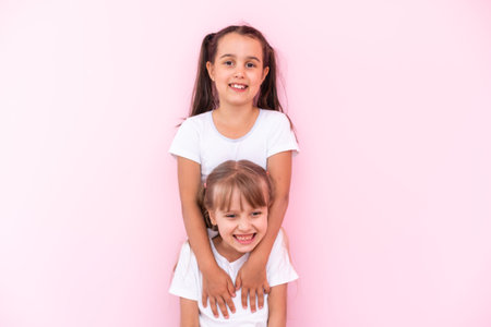 Two little girls - best friends, isolated over on a pink backgroundの写真素材