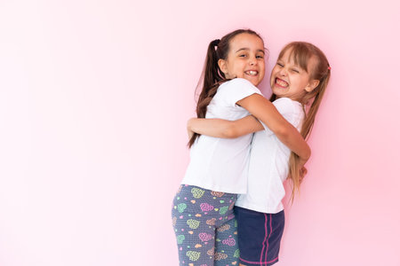 Two little girls - best friends, isolated over on a pink background