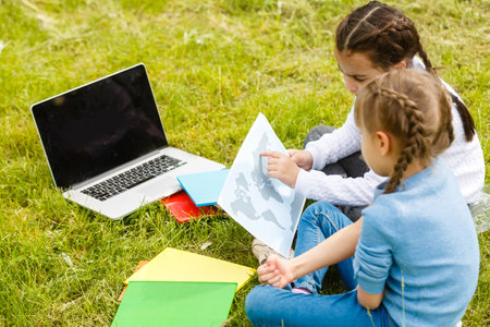 Two beautiful sisters do their homework during quarantine. Children use gadgets for learning. Education, distance learning, home schooling during quarantineの写真素材