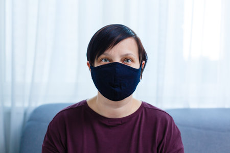 Close up woman portrait, Young woman wearing home made hygienic face medical mask to prevent infection, illness or flu and 2019-nCoV. Black background. Protection against disease, coronavirus.の写真素材