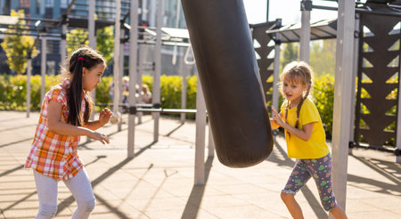 Two cute little girls having fun on a playground outdoors in summer. Sport activities for kids.の写真素材