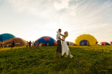 Beautiful romantic couple hugging at meadow. hot air balloon on a backgroundの写真素材