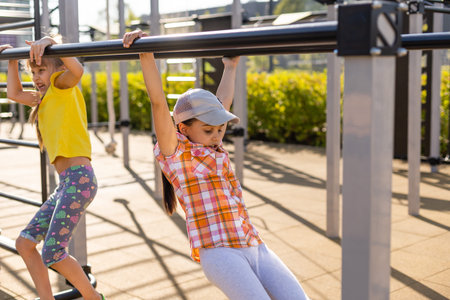 Two cute little girls having fun on a playground outdoors in summer. Sport activities for kids.