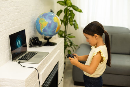 little girl playing games with laptop computer and joystick controllerの写真素材