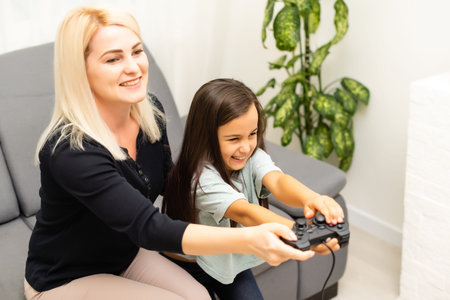 Mother and daughter sittingr in a playroom, playing video games and having fun.