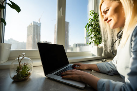 Workplace with notebook laptop Comfortable work table in office with windows and city viewの写真素材