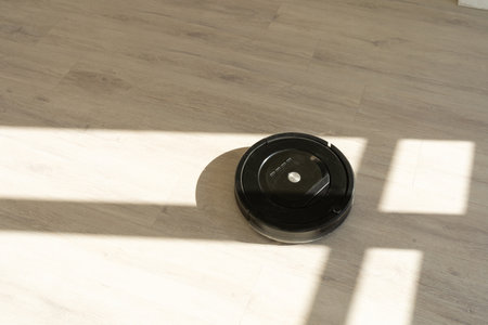 Robotic vacuum cleaner on laminate wood floor in living roomの写真素材