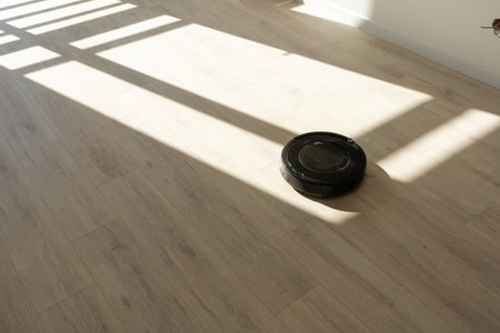 Robotic vacuum cleaner on laminate wood floor in living roomの写真素材