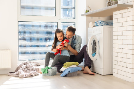 Happy Family loading clothes into washing machine in homeの写真素材